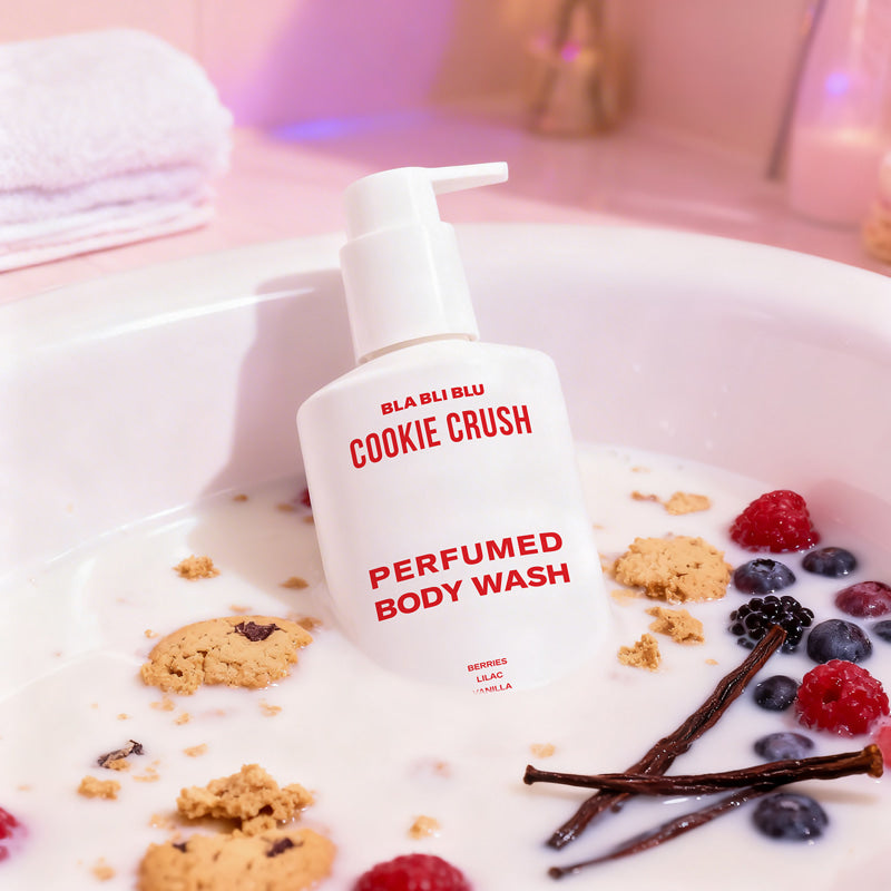 Body wash bottle labeled 'Cookie Crush' on a surface with cookies and berries.