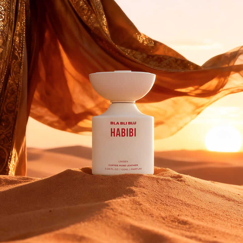 BLA BLU HABIBI perfume bottle in a desert setting with orange fabric and sunset.