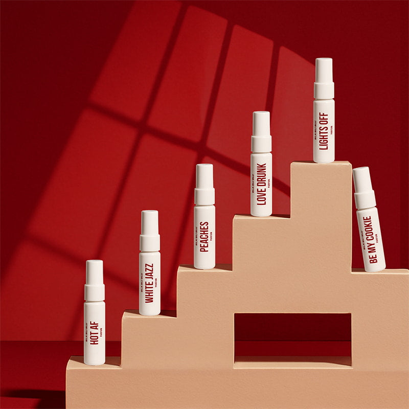 Set of spray bottles on a beige platform against a red background