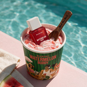A cup of Watermelon Buddy frozen dessert sits by a swimming pool, with a matching red bottle and a wooden spoon placed inside the cup.
