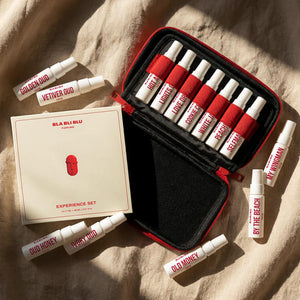 Set of perfume bottles with a red and black case on a beige fabric background