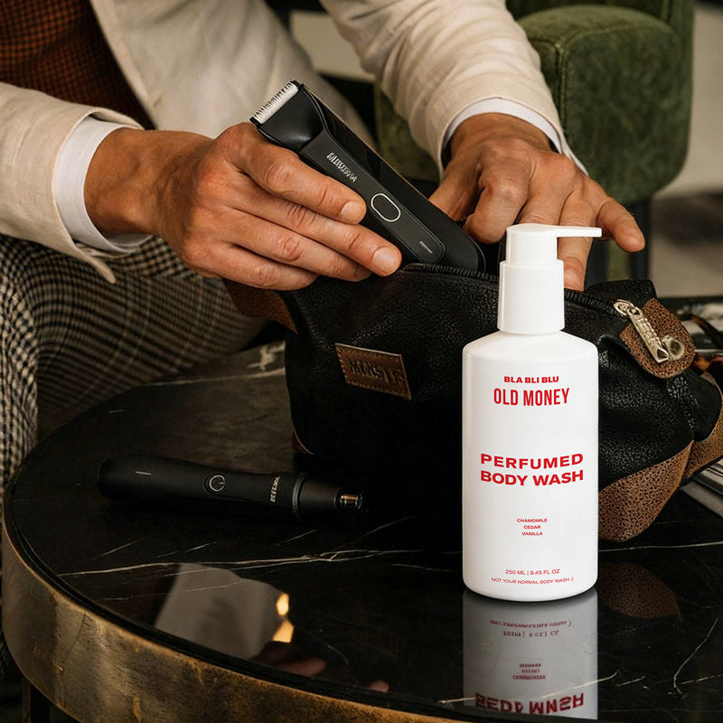 Person holding a grooming tool with a bottle of Old Money body wash on a table.