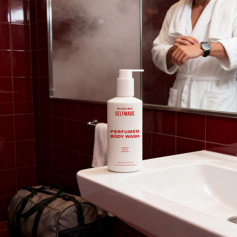 Perfumed body wash bottle on a sink in a bathroom with red tiles.