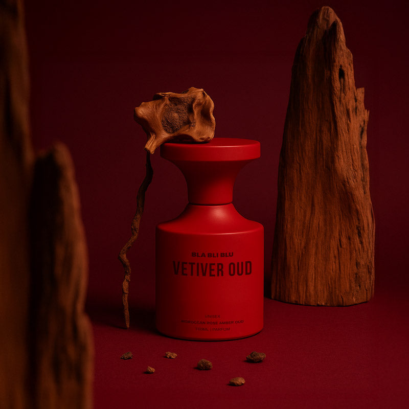 Red perfume bottle labeled 'Vetiver Oud' with wooden elements on a red background